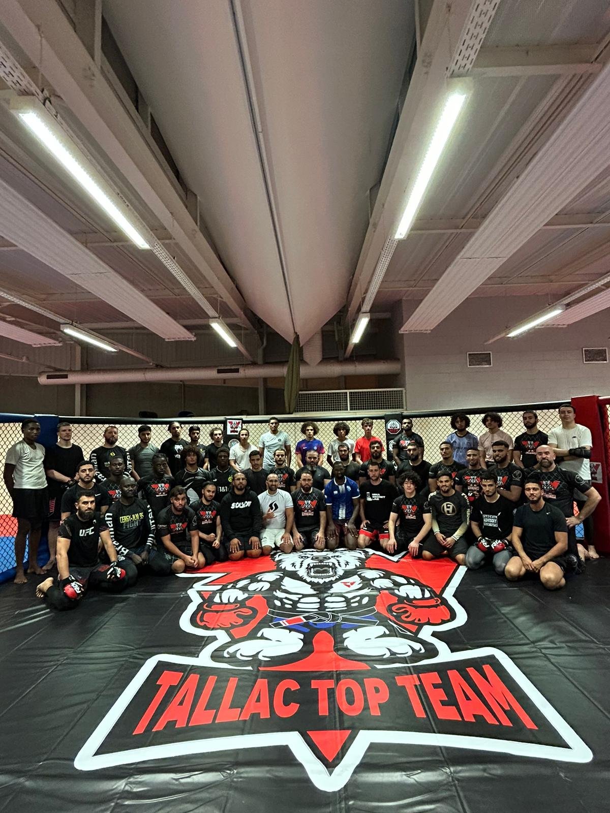 Groupe de combattants MMA Tallac Top Team dans la cage, logo du club au sol